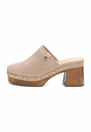 Zoccolo sintetico beige con design perforato, tacco in legno e borchie dorate lungo la suola. Stile con retro chiuso e punta aperta.