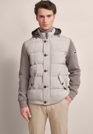 Hellgraue gepolsterte Weste mit einer Kapuze zum Zipper, braunen Knöpfen und grauen Strickärmel. Verfügt über Seitentaschen und ein schlankes Design.