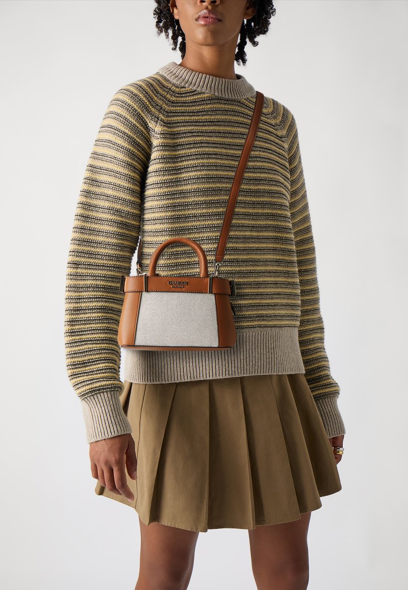 Mała torebka z brązową skórzaną podstawą i jasnym materiałowym korpusem, charakteryzująca się sztywnym kształtem, krótkimi uchwytami i odpinanym paskiem.