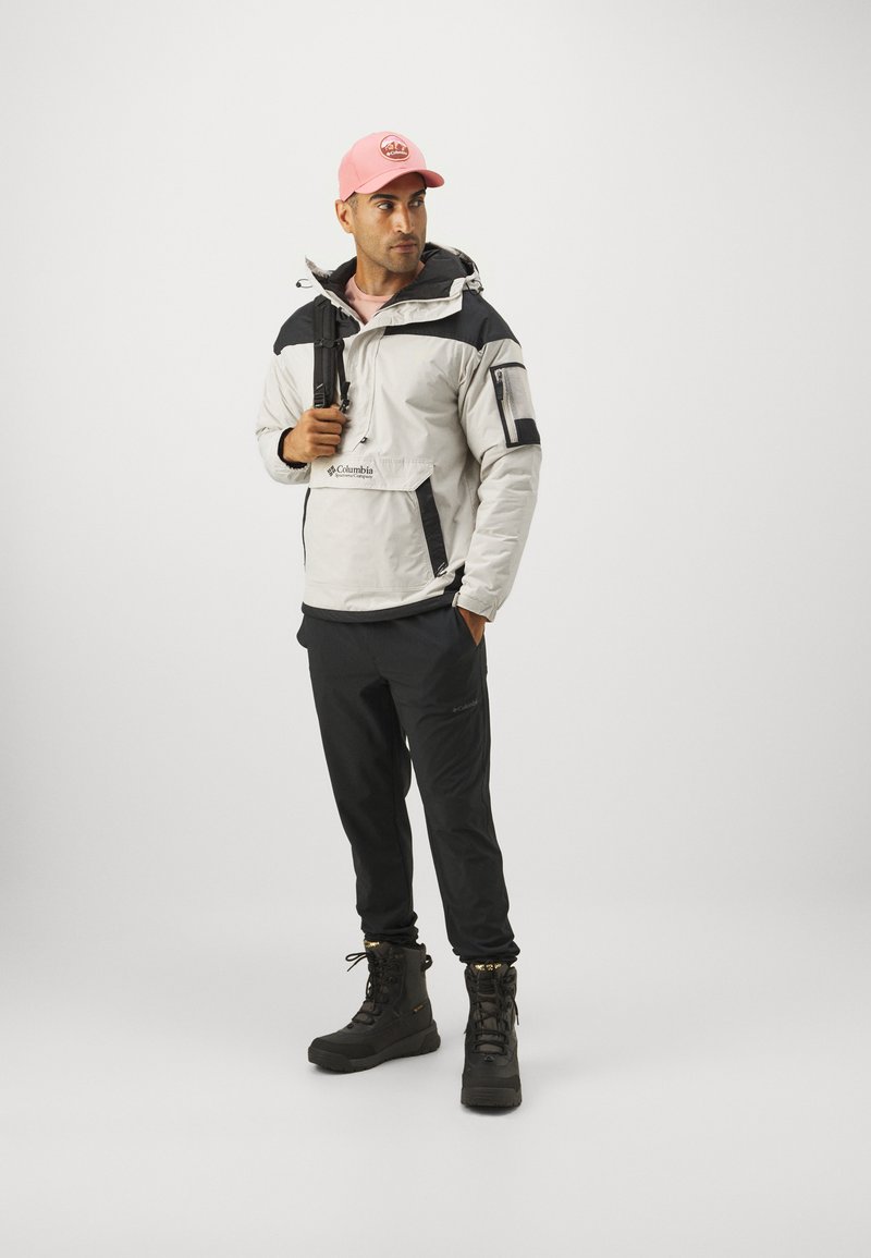 Lekką białą i czarną kurtkę z kapturem i zabezpieczonymi kieszeniami połączono z czarnymi spodniami i ocieplanymi czarnymi butami. Dopełnieniem jest różowa czapka.