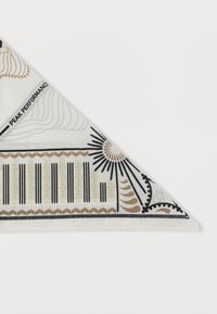 Λευκό τριγωνικό φουλάρι με γεωμετρικά και ηλιακά σχέδια σε μαύρο, μπεζ και χρυσό, με την επιγραφή «PEAK PERFORMANCE» στην μία άκρη.