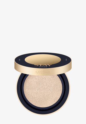Kompakti beige tyynymeikkivoide kultaisessa ja mustassa pyöreässä rasiassa, jossa on merkinnät Stay Cover ja Missha-merkki.