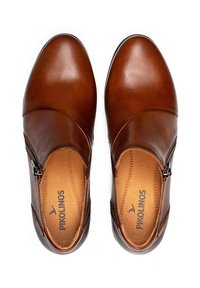 Chaussures en cuir marron avec un bout arrondi, dotées d'une ouverture zippée sur le côté et d'une texture lisse. L'intérieur est doublé d'une couleur claire.