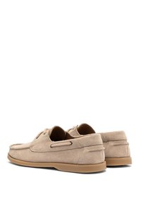 Scarpe da barca in suede beige con punta arrotondata, design con lacci e suole in gomma. Accenti di cucitura notevoli e ritagli laterali per la ventilazione.