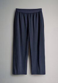 Pantalon en tissu léger bleu marine avec une taille élastique, des jambes larges et une texture lisse, suspendu contre un fond clair.
