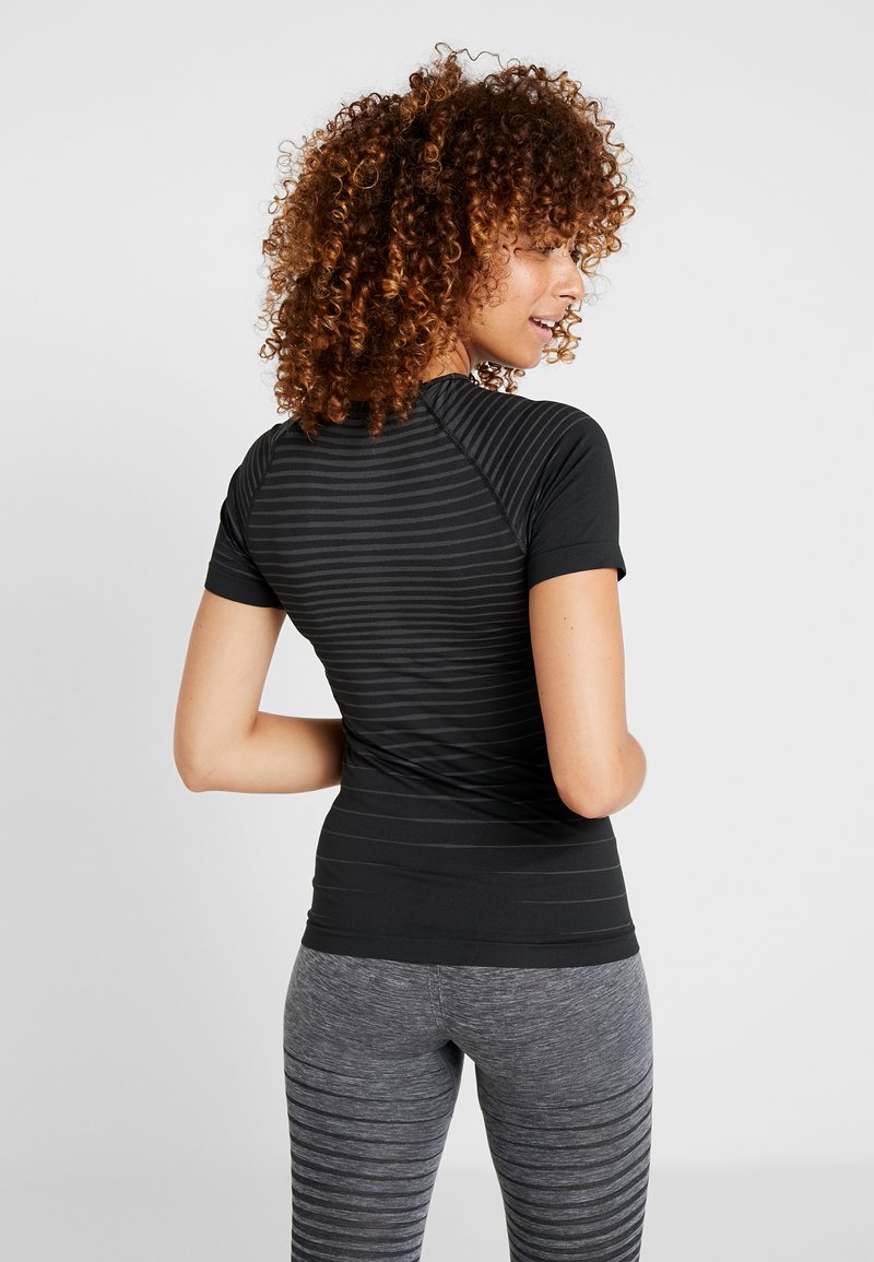 Black short-sleeve athletic top with a textured striped pattern, paired with gray striped leggings, emphasizing a fitted design.