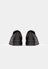Zapatos de cuero marrón con un acabado liso, con detalles de brogue, de perfil bajo y suelas de goma para mayor agarre.