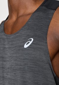 Γκρι αθλητικό tank top με υφή, διαθέτοντας λευκό λογότυ πο στο στήθος και σχεδίαση χωρίς μανίκια για καλύτερη κινητικότητα.