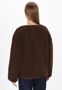 Brown, fluffy fleece sweater with a loose fit, round neckline, and long sleeves. Soft texture and slightly oversized design.