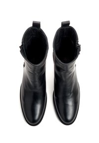 Paire de bottines en cuir noir avec fermetures éclair latérales et languettes, vues de dessus sur un fond blanc.