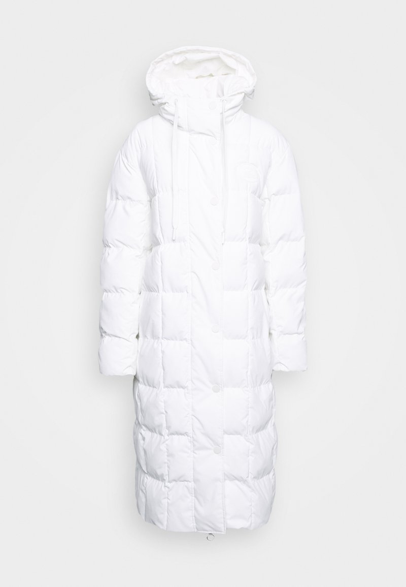 Manteau long blanc en duvet avec capuche, doté d'un design matelassé, d'une fermeture à pression à l'avant, d'un cordon de serrage au niveau du cou et d'un logo rond sur le côté.