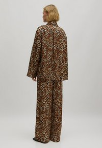 Luipaardprint lounge set met een losvallend shirt en brede broek in bruin en beige tinten met een zachte textuur.
