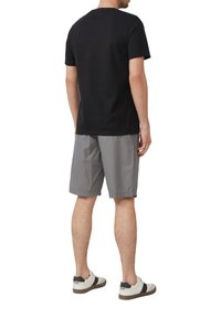 Schwarzes Baumwoll-T-Shirt, graue Shorts und weiße Sneakers. Einfaches Design, kurze Ärmel und Rundhalsausschnitt; die Shorts haben einen elastischen Bund.