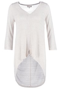 Světle béžový top s dlouhým rukávem a výstřihem do V, s uzlíkem na spodním okraji a prodlouženým zadním dílem. Texturovaná látka má jemné vodorovné pruhy.