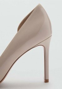 Pantofii stiletto cu toc înalt din piele vernisată nude, cu vârful ascuțit și un toc subțire, având o suprafață netedă și cusături minime.