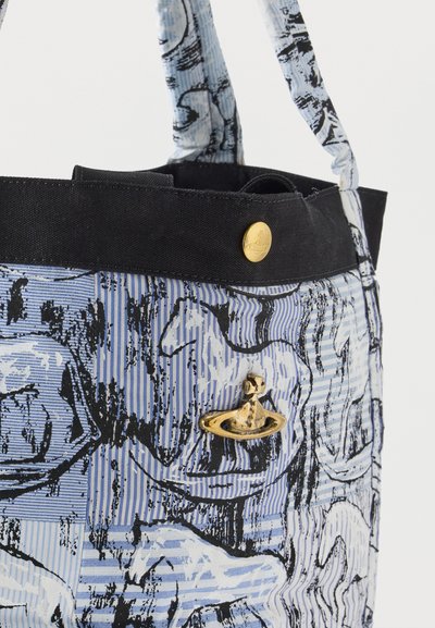 Τσάντα ώμου με μπλε και λευκό σχέδιο, μαύρο περίγραμμα, χρυσό κουμπί και χρυσό λογότυπο σε σχήμα σφαίρας στην υφασμάτινη επιφάνεια.