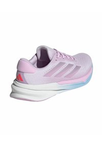 Hellrosa Sportschuh mit einem atmungsaktiven Mesh-Obermaterial, weißer Zwischensohle und blauer Außensohle. Verfügt über drei horizontale Streifen und einen gepolsterten Kragen.