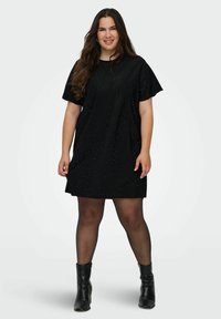 Melna t-kreklu kleita ar īsām piedurknēm, kas ir ar maziem mirdzošiem akcentiem, brīvs piegriezums, līdz ceļiem, saskaņota ar melniem potīšu zābakiem.