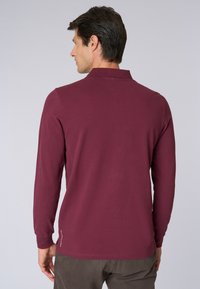 Polo a maniche lunghe color bordeaux con colletto a costine, vestibilità dritta e dettaglio logo discreto all'orlo. Tessuto in cotone morbido.