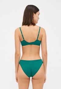 Teal bikiniset som har et enkelt bralette-design med justerbare stropper og matchende høyt skårne truser. Laget av glatt, elastisk stoff.
