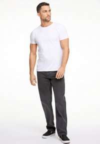 Camiseta blanca de cuello redondo combinada con jeans rectos de color gris oscuro y zapatos negros de tipo slip-on. El conjunto presenta un ajuste relajado y un estilo casual.