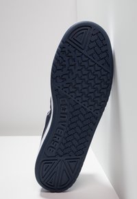 Námořnická gumová podrážka tenisky s texturovaným gripem, obsahující logo "Converse" a trojúhelníkový detail v oblasti prstů.