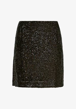 Kobieta ubrana w czarną bluzkę zapinaną na guziki, czarną cekinową spódnicę do kolan oraz czarne mulesy na wysokim obcasie z odkrytymi palcami, stojąca na jednolitym tle.