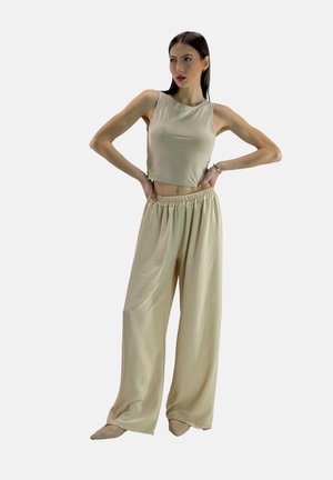 Crop top beige e pantaloni a gamba larga realizzati in un tessuto morbido e leggero. Presentano una vita elastica e una texture liscia.