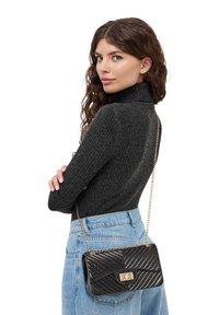Borsa nera trapuntata con tracolla in oro; presenta una superficie texturizzata e una forma rettangolare con chiusura a gancio.