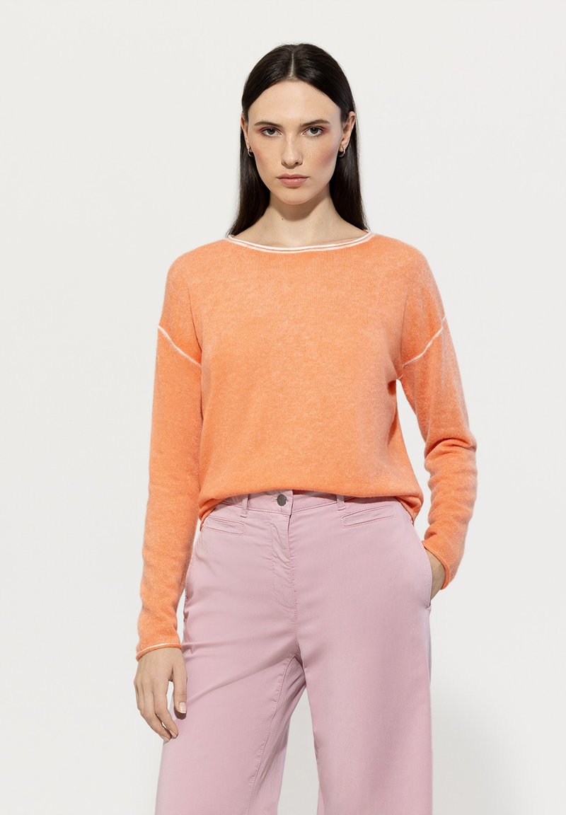 Lightweight orange sweater with a loose fit, round neckline, and contrasting white stitching. Paired with soft pink straight-leg pants.