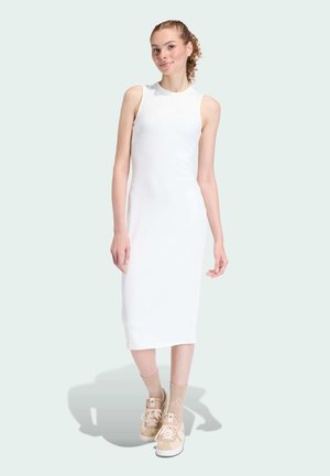White ribbed midi dress with a sleeveless design, paired with beige sneakers and patterned socks, against a light green background.