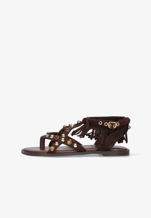 Sandalo flat marrone con cinturino alla caviglia, dettaglio con frange e borchie tonde multicolori sulle fasce incrociate.