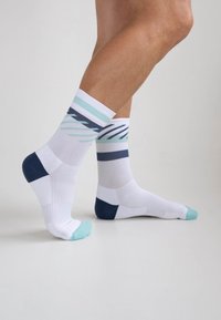 White socks with navy, light blue, and turquoise accents, featuring a geometric pattern and a ribbed cuff for added comfort and texture.