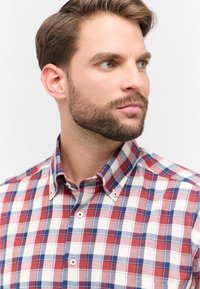 Camicia button-down a quadri rossi, blu e bianchi con colletto e bottoni bianchi, realizzata in un tessuto di cotone morbido.