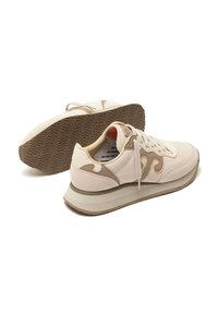 Sneaker casual beige e crema con lacci, suole spesse e suole in gomma marchiate, una scarpa poggiata di lato e l'altra in posizione verticale.