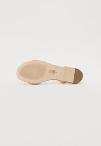 Transparent pink sandal sole featuring a textured, ribbed surface and a solid beige heel section, with brand markings engraved.
