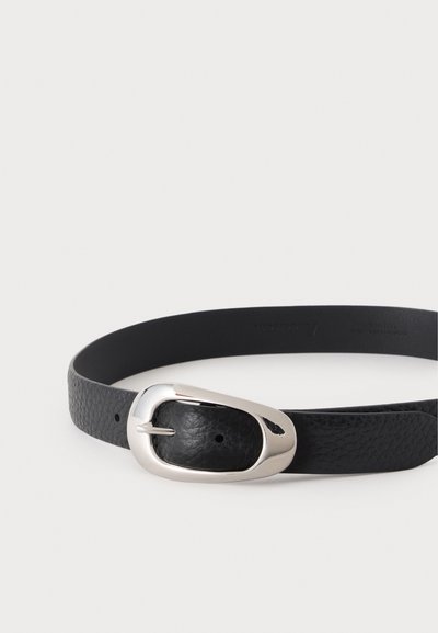Ceinture en cuir noir texturé avec une boucle ovale argentée brillante, posée à plat sur un fond clair.