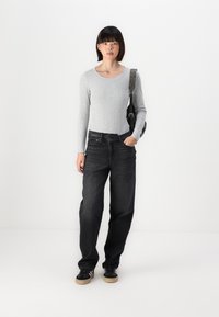Long-sleeve light gray ribbed top, black wide-leg jeans, and black sneakers with gum soles. Carrying a gray shoulder bag.