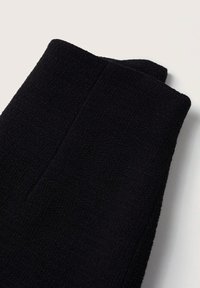 Tissu noir texturé présentant un motif tissé avec une forme structurée. Les bords sont finement finis.