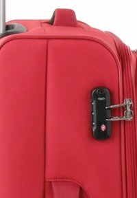 Valigia rigida rossa con manico trolley, dotata di una combinazione nera, texture liscia e cerniere rinforzate. Design compatto e resistente.