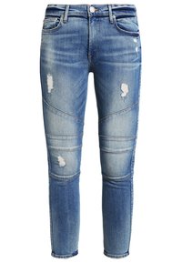 Vaqueros de mezclilla azul con un corte Slim Fit, que cuentan con parches desgastados, textura descolorida, paneles en las rodillas y un diseño clásico de cinco bolsillos.