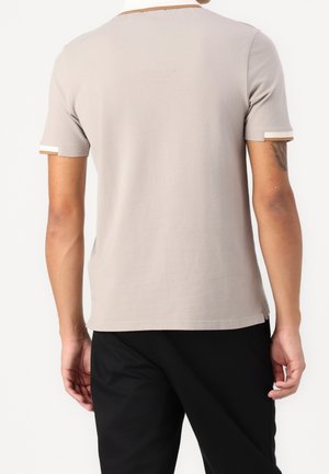 Beiges Baumwoll-T-Shirt mit kurzen Ärmeln, das einen kontrastierenden hellen Halsausschnitt und farbige Akzente an den Ärmelabschlüssen aufweist. Glatte Textur, reguläre Passform.