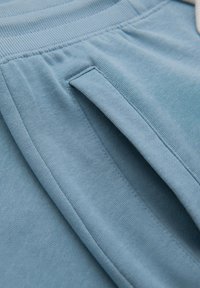 Blauwe katoenstof met een gladde textuur, met een gestikte tailleband en een zijzakdetail.