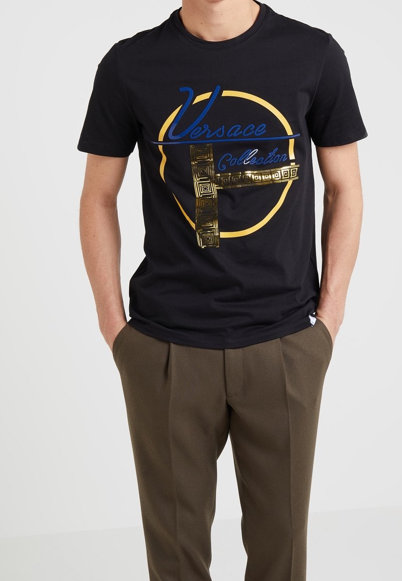Svart bomull T-shirt med blå "Versace" text och guld geometrisk mönsterdesign, rund halsringning, korta ärmar och normal passform.