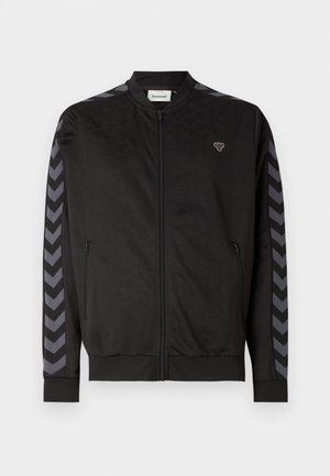 Veste de sport noire avec fermeture éclair à l'avant, texture en relief, poignets côtelés et rayures en chevrons gris contrastantes sur les manches.