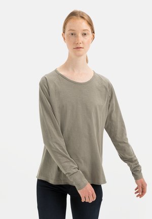 Langärmeliges Hemd in Olivgrün, aus weichem Stoff, mit runder Ausschnitt und lockerer Passform, getragen mit dunklen Jeans.