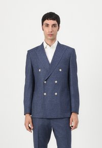 Sacou bleumarin cu două rânduri de nasturi, dintr-un material texturat, având nasturi metalici și două buzunare frontale, asortat cu o cămașă albă.
