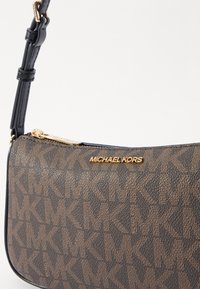 Brązowa syntetyczna torba o teksturowanym wykończeniu, z wzorem monogramu oraz złotym akcentem logo, wyposażona w odpinany czarny pasek.