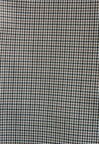 Motif textile pied-de-poule marron, noir et blanc avec de petits carreaux en dents de scie dans une formation en grille répétitive.