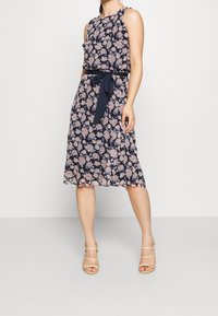 Bezramínková námořnická šaty s květinovým vzorem v odstínech růžové, s opaskem v pase, splývavou sukní a průhlednou texturou látky.